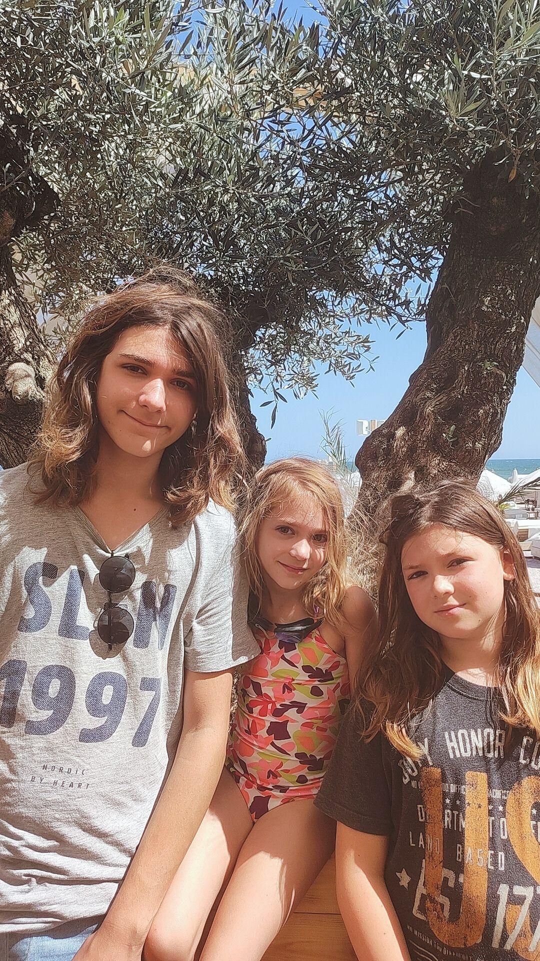 Her three children under an olive tree by the sea.